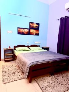 Un dormitorio con una cama y una pared azul. en Vedic Villa, en Alleppey