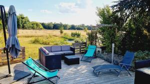 a patio with chairs and a couch and an umbrella at Maison avec jardin proche des bords de Loire in Les Ponts-de-Cé