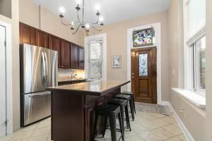 a kitchen with a bar with stools and a refrigerator at The Gathering Spot Downtown St. Louis by StayLage in Soulard