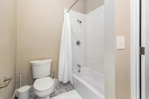 a white bathroom with a toilet and a shower at The Gathering Spot Downtown St. Louis by StayLage in Soulard +37 photos