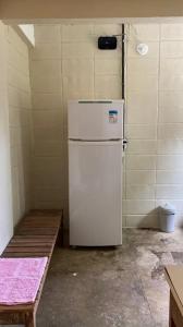 a white refrigerator in a room with a table at Chalé - Praia in Ubatuba