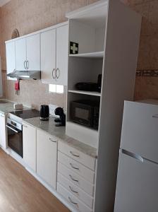 a kitchen with white cabinets and a white refrigerator at Cantinho da Cruz in Ponta Delgada