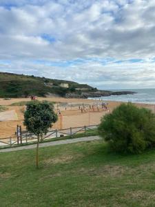 a beach with people on the sand and the ocean at Chalet en Costa Quebrada - Soto de la Marina in Santa Cruz de Bezana