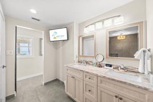 a bathroom with a sink and a tv on the wall at The Banana River Resort in Cocoa Beach +149 photos