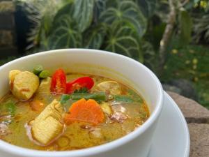 Un tazón blanco de sopa con verduras. en sena guesthouse, en Munduk