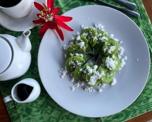 Un plato blanco con verduras cubiertas de nieve sobre una mesa. en sena guesthouse, en Munduk