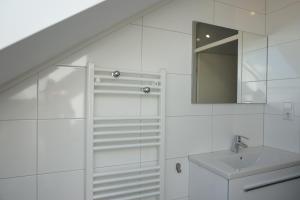 a white bathroom with a sink and a mirror at Kustverhuur, Vakantiepark Fort Soleil 26 in Breskens +9 photos