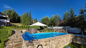 a swimming pool in a yard with a stone wall at L - Hutir in Mykulychyn