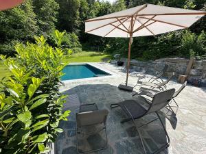 a patio with chairs and an umbrella and a pool at Forsthaus Gradisch in Feldkirchen in Kärnten