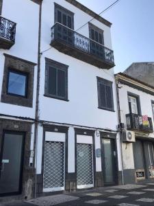 a white building with black windows and a balcony at Cantinho da Cruz in Ponta Delgada