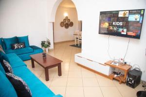 Una sala de estar con un sofá azul y un televisor. en Ndoto House, en Ukunda