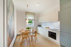 eine Küche mit weißen Schränken und einem Tisch und Stühlen in der Unterkunft NORTH Apartments, Vibe Ustka in Ustka