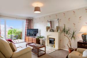 a living room with a fireplace and a television at 70 Abbotsbury Road, Bury St Edmunds, IP33 2HP in Moffat