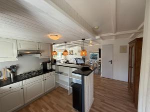 a kitchen with white cabinets and a black counter top at Boshuis Bubbels Wellness Chalet with Private HOTTUB and SAUNA - Super Holiday House with Huge Garden and Private Parking Space - Veluwe Holiday Voorthuizen in Voorthuizen