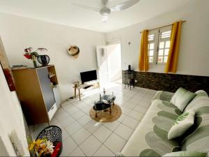 a living room with a couch and a television at Abri Papaye in Rivière-Salée