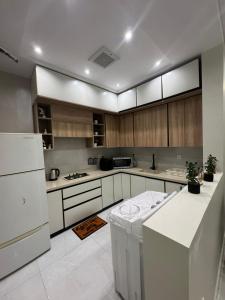 a kitchen with white appliances and wooden cabinets at دايموند جدة للشقق الفاخرة in Jeddah
