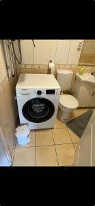 een wasmachine in een badkamer met toilet bij Noemi Appartman Szeged in Szeged +8 foto's