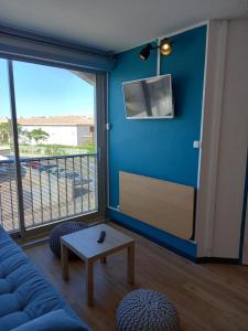 ein Wohnzimmer mit einer Couch, einem Tisch und einem Fernseher in der Unterkunft La Vie en Rose Cosy Proche du Port in Gruissan