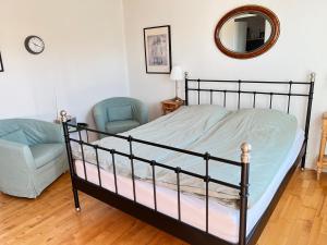 a bedroom with a bed and a chair and a mirror at Eddies Bed & Breakfast in Skagen