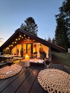 a wooden table with two glasses of wine and a candle at Unique forest cabin by lake near Legoland, ForestCabinDK in Ansager