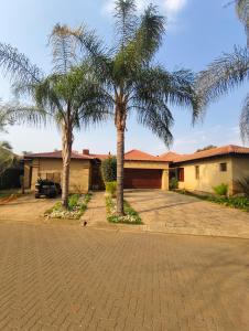 a house with two palm trees in the driveway at Forest Crescent Villa - Pecanwood Golf Estate, Hartbeespoort in Hartbeespoort +17 photos