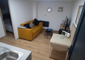 a living room with a yellow couch and a table at Appartement 5min du centre ville et gare in Schiltigheim +2 photos