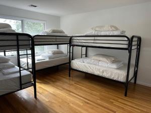three bunk beds in a room with a wooden floor at Brill St hostel in Newark