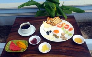 a table with a plate of breakfast food and a cup of coffee at Angkor Gecko's Inn Hotel & Guesthouse in Siem Reap