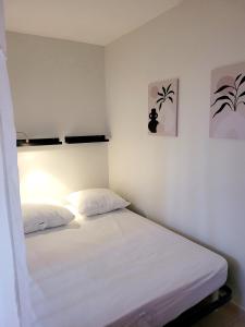 Un dormitorio con dos camas con sábanas blancas. en La Petite Escale, en Lunel