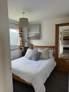 a bedroom with a bed with white sheets and a mirror at The Beach Hut in Perranporth