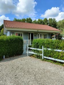 a house with a white fence in front of it at Le cottage des rives de l'Aa labélisé 3 étoiles in Bourbourg