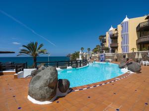 a swimming pool with rocks in front of a resort at Altamar 60 Balcony beach views By CanariasGetaway in Playa del Aguila
