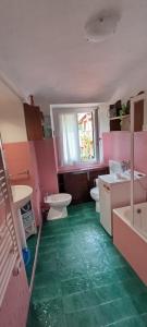 une salle de bains rose avec deux toilettes et un sol vert dans l'établissement La terrazza di Ameglia alta - relax nel borgo Ligure, à Ameglia