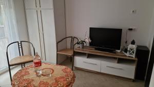 a living room with a tv on a stand with a table at Villa Olga in Hévíz