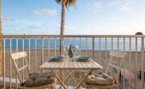 a table and chairs on a balcony with the beach at Frente al mar y a pie de playa in Torrenueva