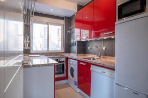 a kitchen with red cabinets and a washer and dryer at Frente al mar y a pie de playa in Torrenueva