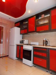 ナーベレジヌイェ・チェルヌイにあるApartments on Adelya Kutuya 3のキッチン(赤いキャビネット、白い冷蔵庫付)