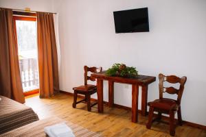 Una sala de estar con una mesa y sillas y un televisor. en Гук готельно-ресторанний комплекс, en Bukovel