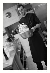 ラプートロワにあるHôtel Restaurant Les Alisiersの鉢花を持つ台所の男