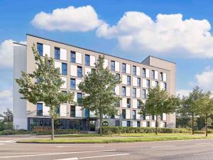 ein großes weißes Gebäude mit Bäumen davor in der Unterkunft B&B Hotel Köln-Messe in Köln