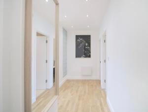 a hallway with white walls and wood floors and a mirror at Large City Centre Apartment Stylish and Spacious in Manchester
