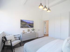 a white bedroom with a white bed and a chair at Large City Centre Apartment Stylish and Spacious in Manchester