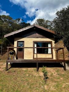 a small house with a porch on a field at Chalés Retiro dos Manacás in Sapucaí-Mirim