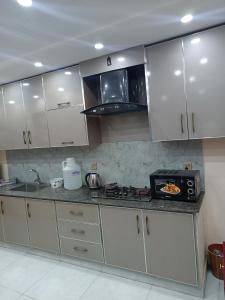 a kitchen with white cabinets and a stove top oven at One bed apartment in Lahore in Lahore