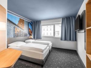 a hotel room with two beds and a television at B&B Hotel Schweinfurt-City in Schweinfurt
