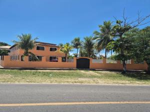 a house with a fence and palm trees at Pousada Imperatriz in Itaparica