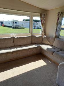 a couch in a living room with a large window at J & C caravans in Saint Osyth