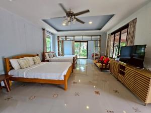 a bedroom with two beds and a flat screen tv at The Leaf Pool Villa Resort in Muak Lek District