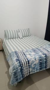 a bed with a blue and white blanket on it at la casita de Daniela in San Miguel