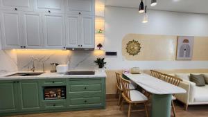 une cuisine avec des placards verts, une table et un canapé dans l'établissement Homestay 2PN, 1719 - Chung cư Sentosa Sky Park - Hải Phòng - 2 Bedroom Apartment for Rent, à An Khê